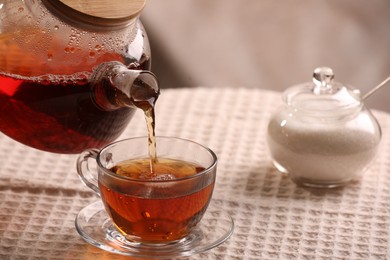 Photo of Pouring aromatic tea into cup at table, closeup