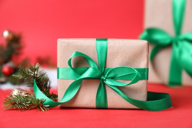 Photo of Christmas gift box and fir branches on red background, closeup