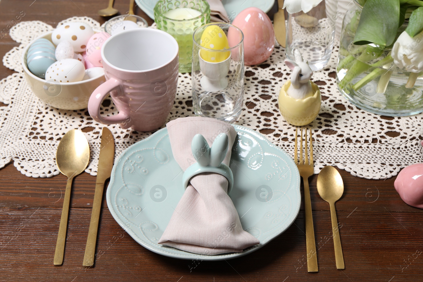 Photo of Festive table setting with napkin ring in shape of bunny ears. Easter celebration