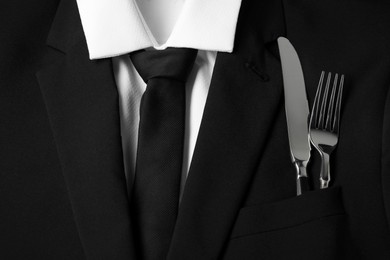 Man's jacket with cutlery as background, closeup. Business lunch concept