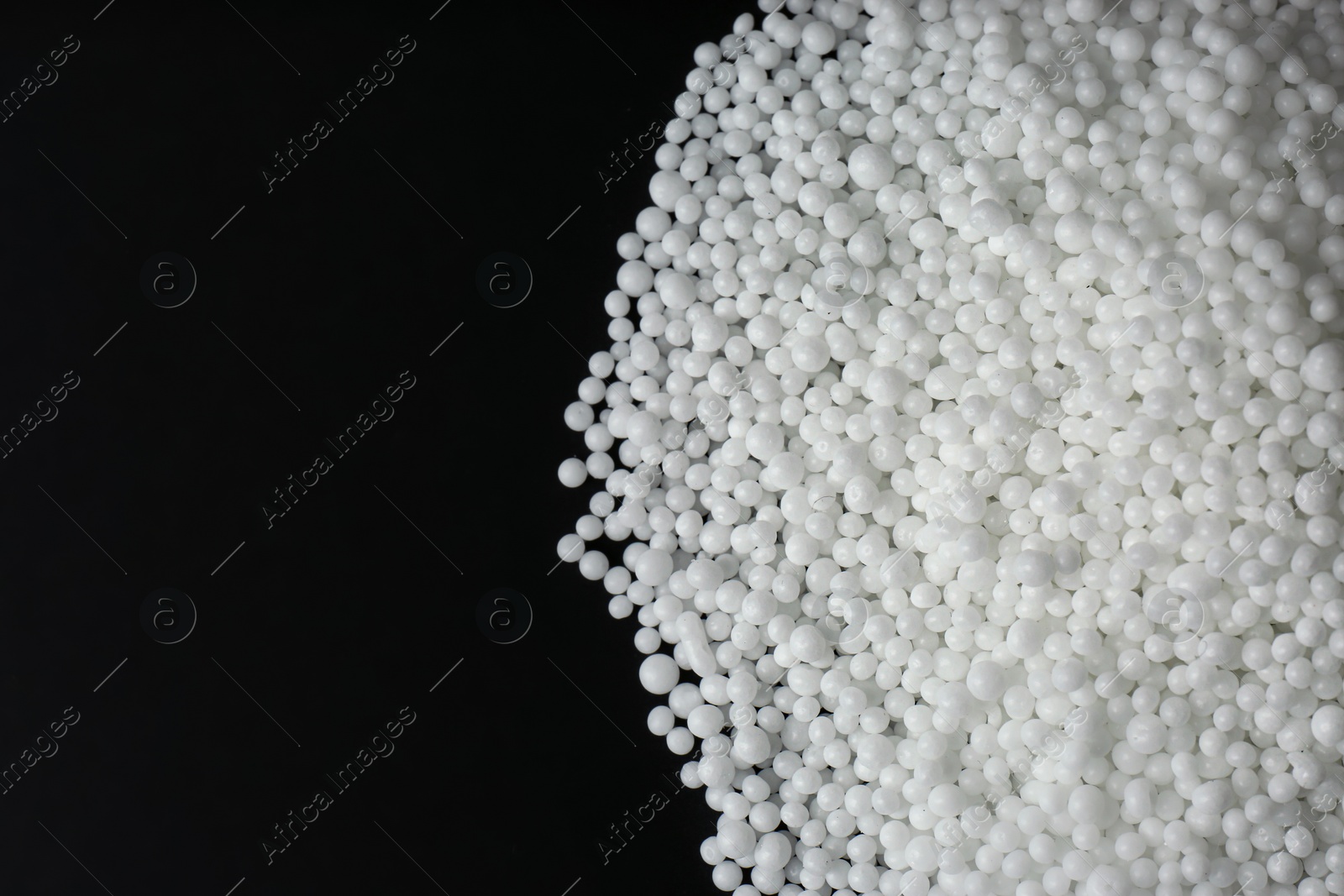 Photo of Pellets of ammonium nitrate on black background, flat lay with space for text. Mineral fertilizer