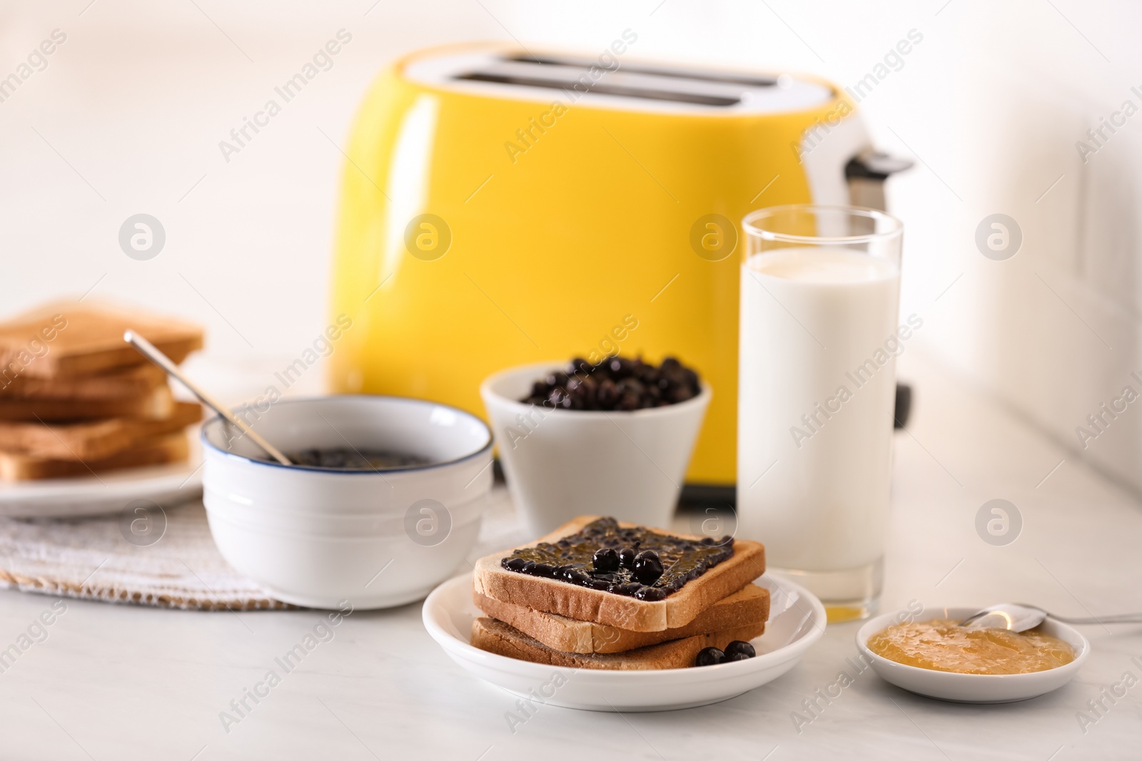 Photo of Modern toaster and delicious breakfast on table in kitchen
