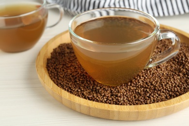 Photo of Delicious buckwheat tea and granules on white wooden table