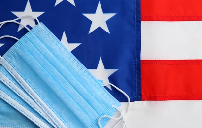 Photo of Medical masks on American flag, flat lay. Coronavirus pandemic in USA