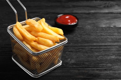 Photo of Tasty french fries and ketchup on dark wooden table, closeup. Space for text