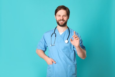 Photo of Happy doctor or medical assistant (male nurse) with stethoscope on turquoise background