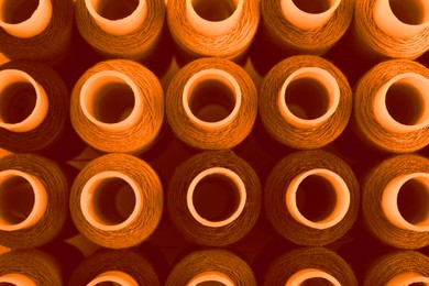 Image of Spools of sewing threads as background, top view. Toned in orange