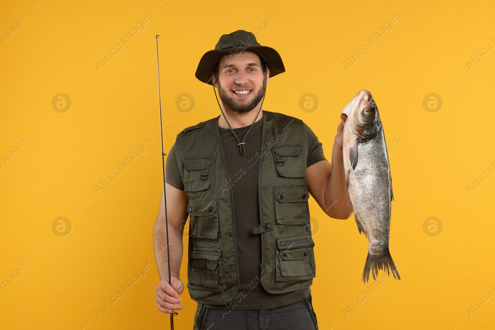 Photo of Fisherman with rod and catch on yellow background