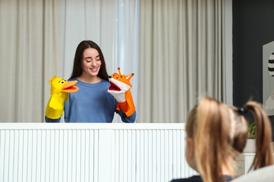 Photo of Mother performing puppet show for her daughter at home