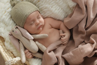 Photo of Cute newborn baby with toy bunny sleeping in cradle, top view