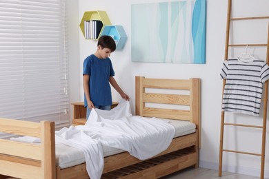 Photo of Boy changing bed linens in children room