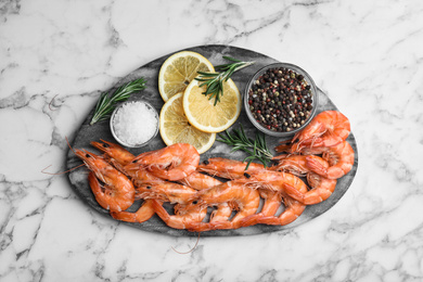 Delicious cooked shrimps served with rosemary and lemon on white marble table, top view