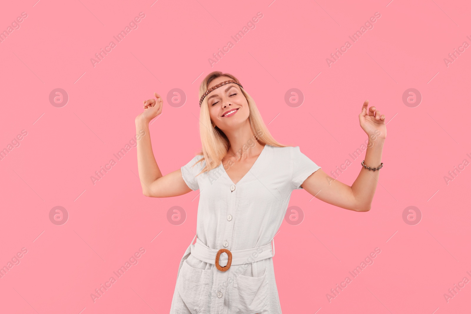 Photo of Portrait of smiling hippie woman dancing on pink background