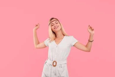 Portrait of smiling hippie woman dancing on pink background