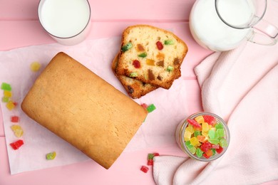 Photo of Delicious cake with candied fruits and milk on pink wooden table, flat lay