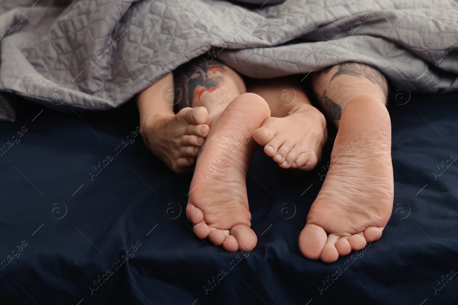 Photo of Passionate couple having sex on bed, closeup of legs