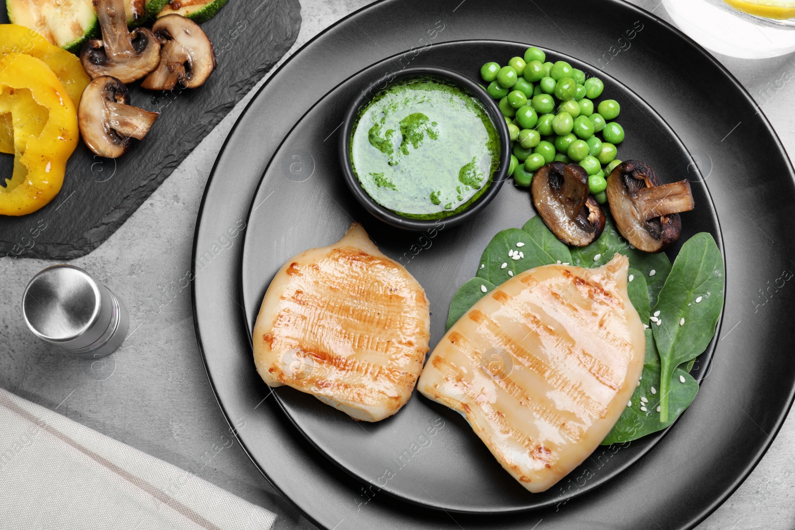 Photo of Grilled squid tubes served on grey table, flat lay