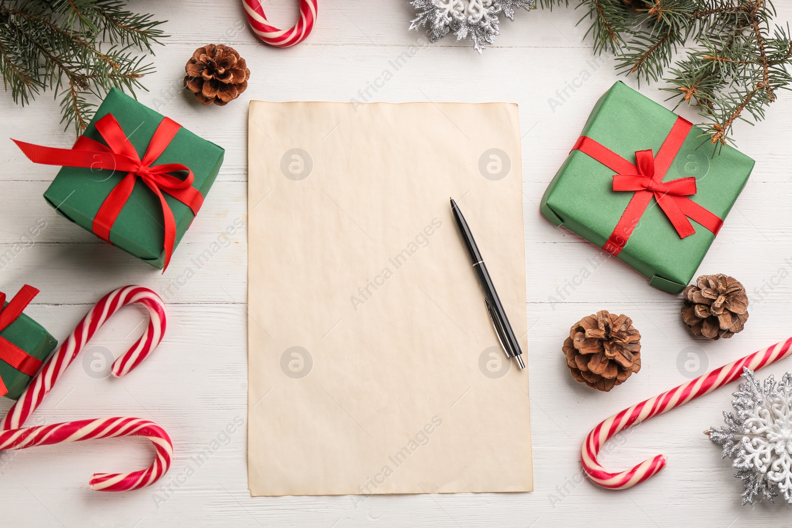 Photo of Flat lay composition with paper and Christmas decor on white wooden table. Writing letter to Santa Claus