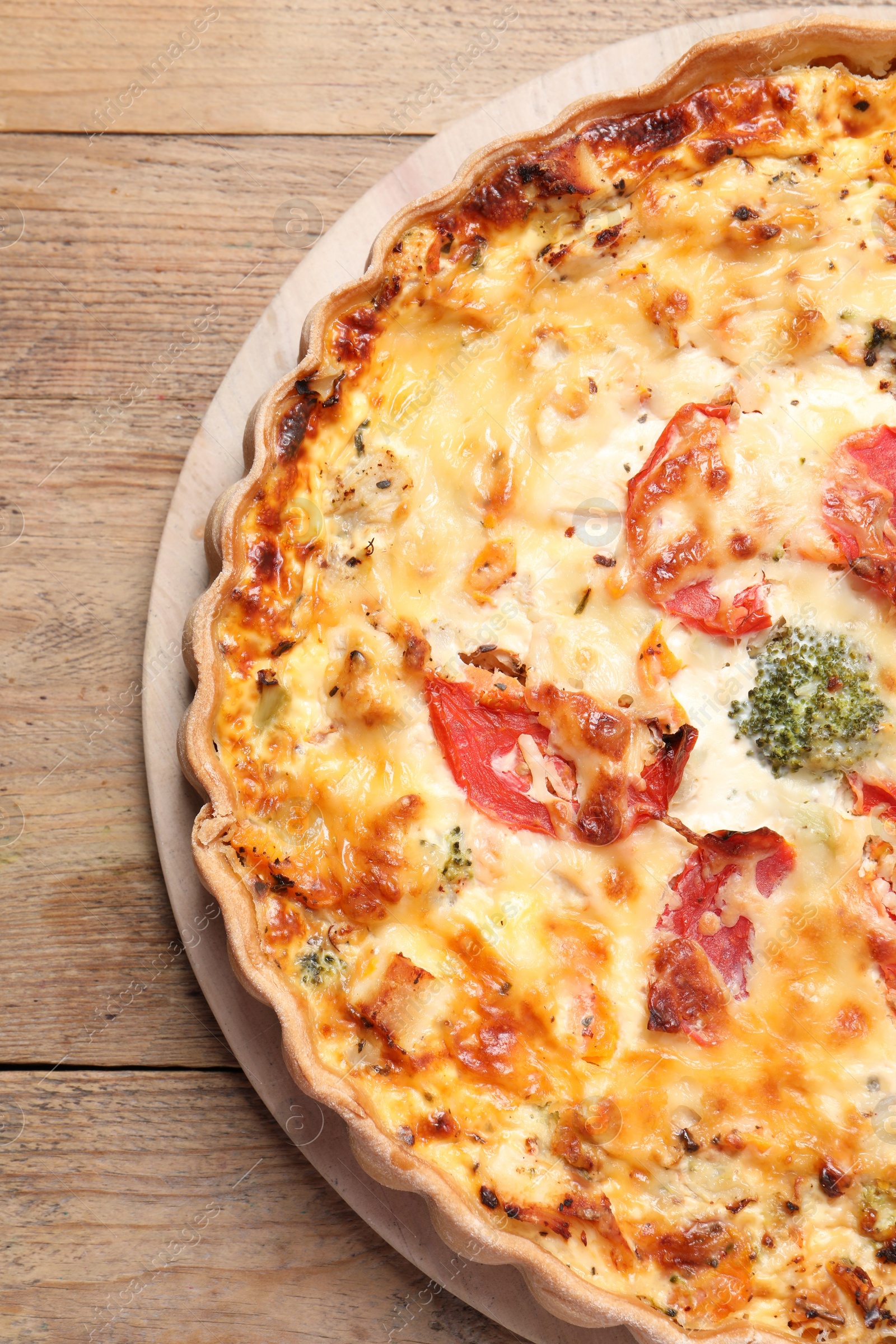Photo of Tasty quiche with tomatoes and cheese on wooden table, top view