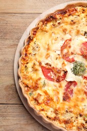 Tasty quiche with tomatoes and cheese on wooden table, top view