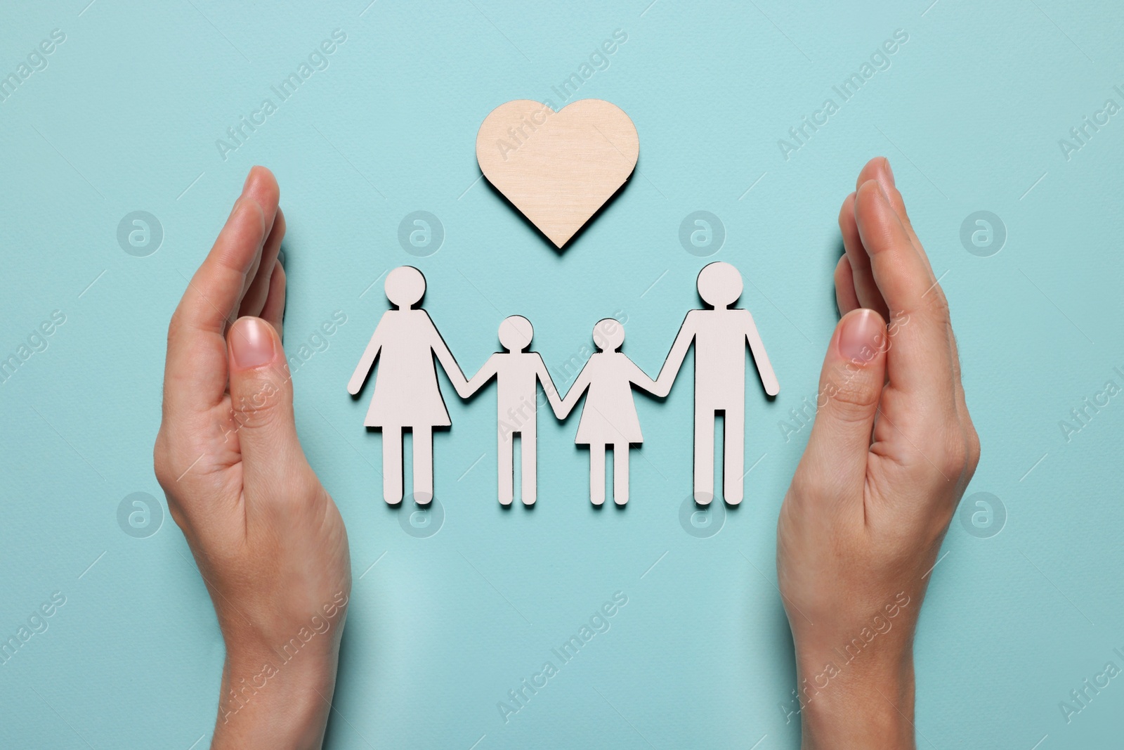 Photo of Woman protecting figures of family and heart on light blue background, top view. Insurance concept