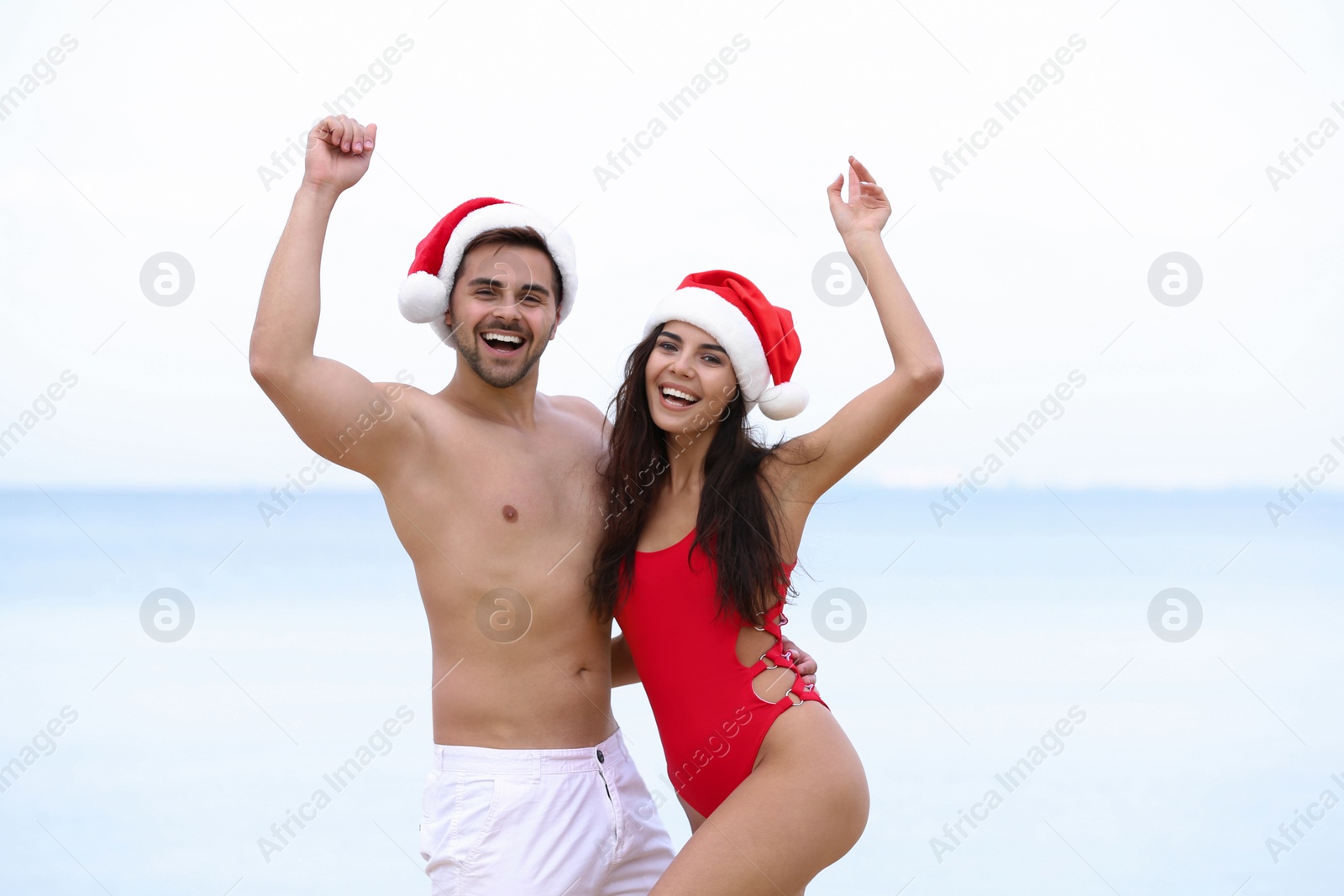 Photo of Happy young couple with Santa hats together on beach