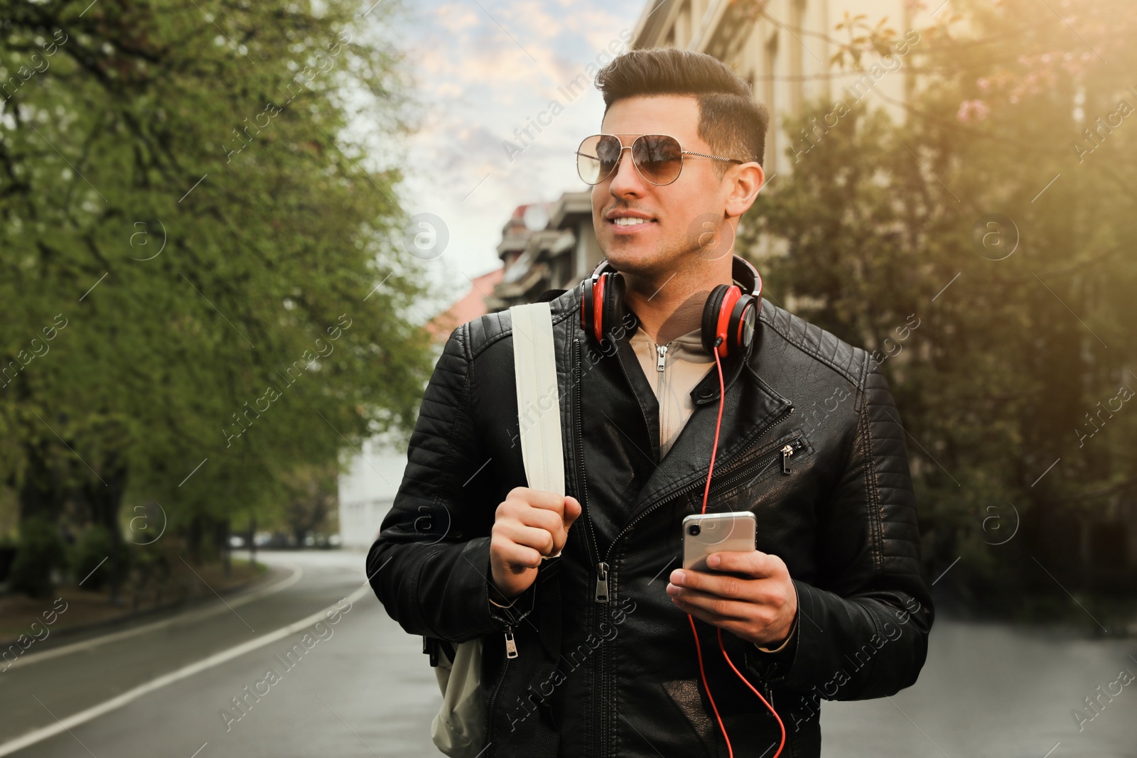 Photo of Tourist with smartphone and headphones on city street