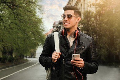 Photo of Tourist with smartphone and headphones on city street