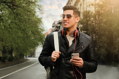 Tourist with smartphone and headphones on city street