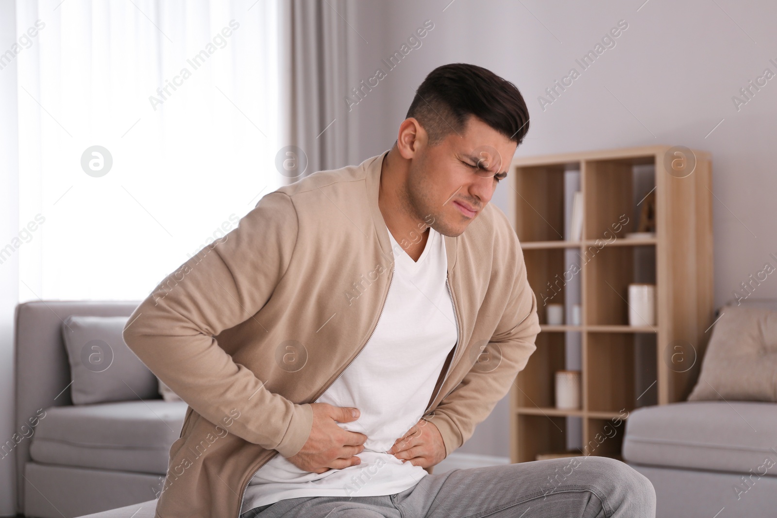 Photo of Man suffering from stomach ache at home. Food poisoning