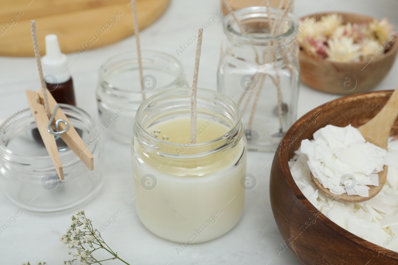 Photo of Glass jars with wicks and wax on white table. Making homemade candles