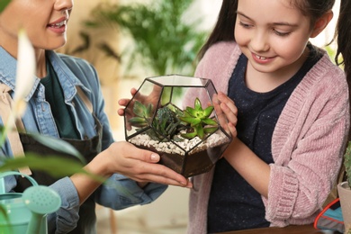 Photo of Mother and daughter taking care of plants at home, closeup