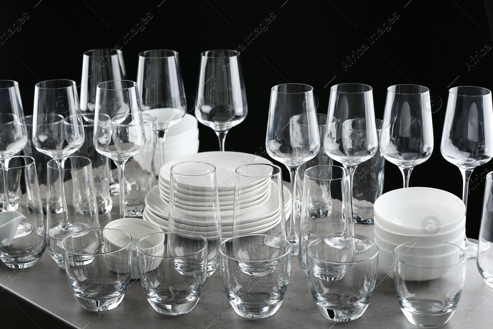 Photo of Set of empty glasses and dishware on table against black background