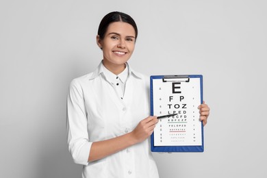 Photo of Ophthalmologist pointing at vision test chart on light background