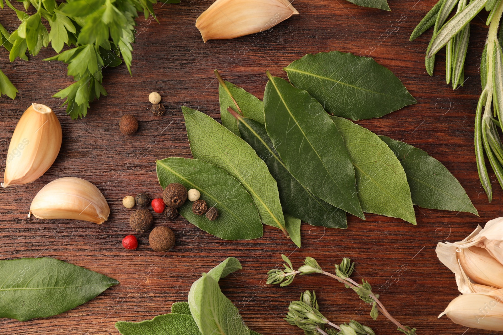 Photo of Aromatic bay leaves, different herbs and spices on wooden table, flat lay