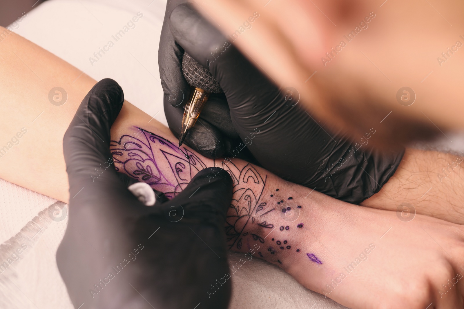 Photo of Professional artist making tattoo on hand at table, closeup