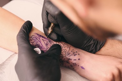 Professional artist making tattoo on hand at table, closeup