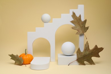 Autumn presentation for product. Geometric figures, pumpkin and dry leaves on beige background