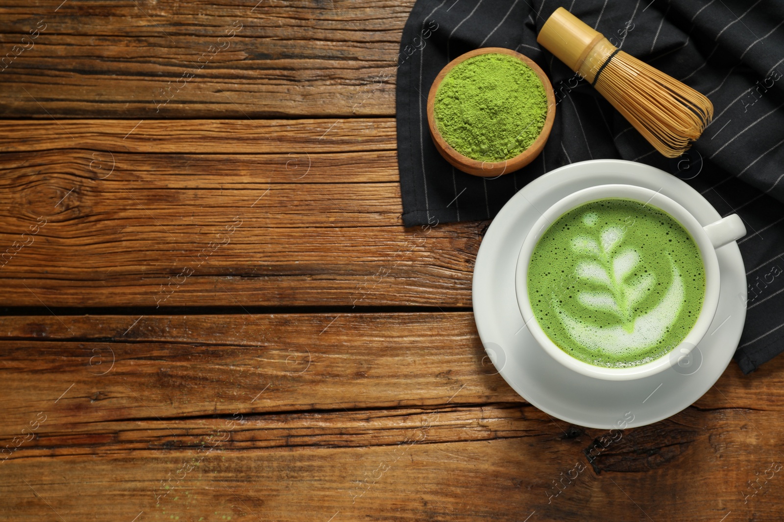 Photo of Delicious matcha latte, powder and whisk on wooden table, flat lay. Space for text