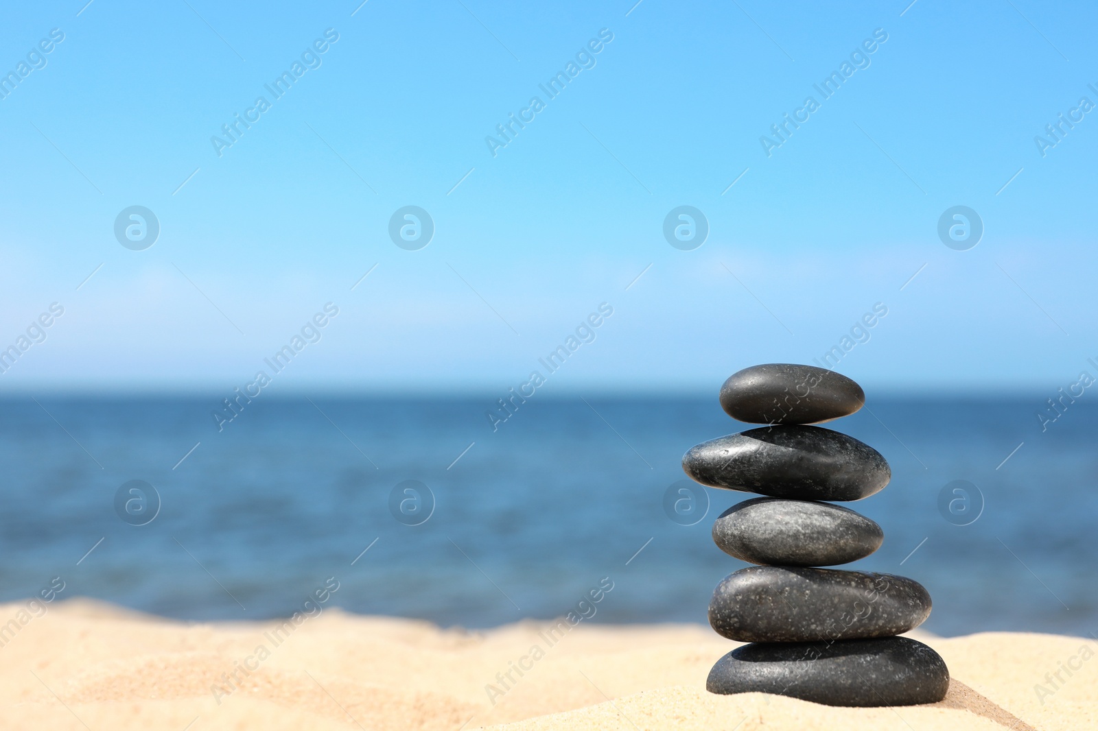 Photo of Stack of stones on sand near sea, space for text. Zen concept