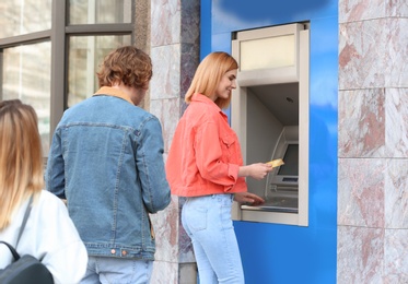 People standing in queue to cash machine outdoors