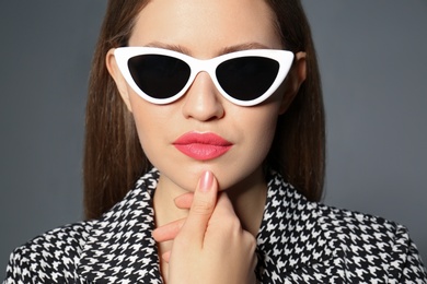 Photo of Young woman wearing stylish sunglasses on grey background