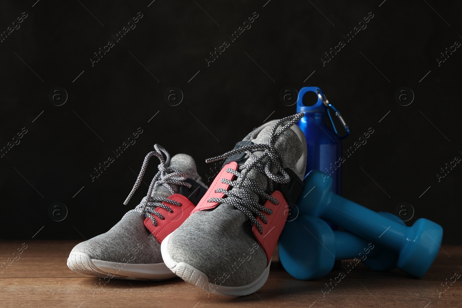 Gym equipment and accessories on wooden floor against dark background Photo of Gym equipment and accessories on wooden floor against dark background
