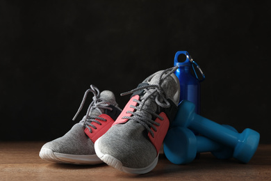 Photo of Gym equipment and accessories on wooden floor against dark background