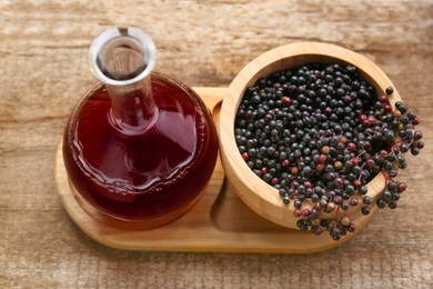 Elderberry wine and bowl with Sambucus berries on wooden table, above view