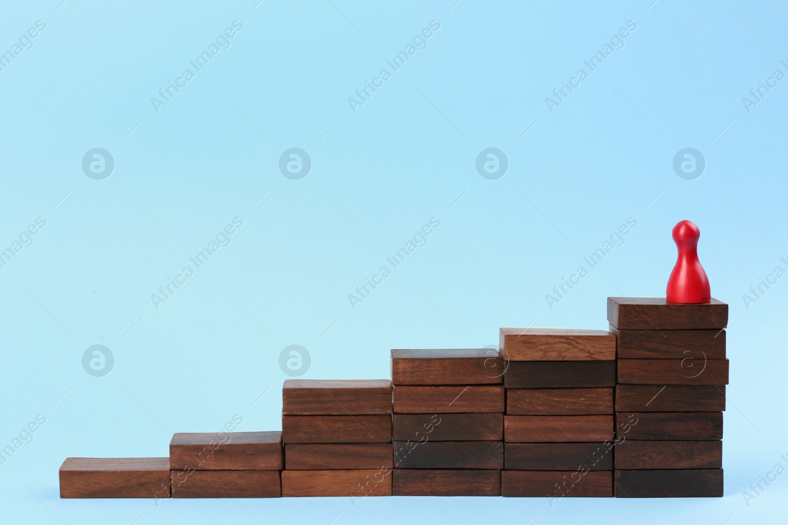 Photo of Red piece on wooden stairs against light blue background. Career promotion concept