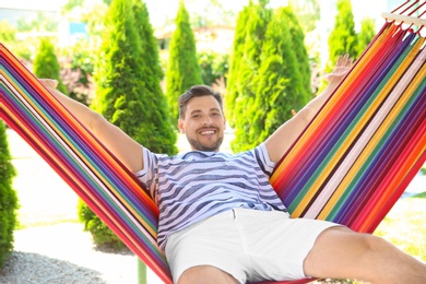 Photo of Man relaxing in hammock outdoors on warm summer day