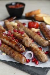 Photo of Tasty grilled sausages served on light table, closeup