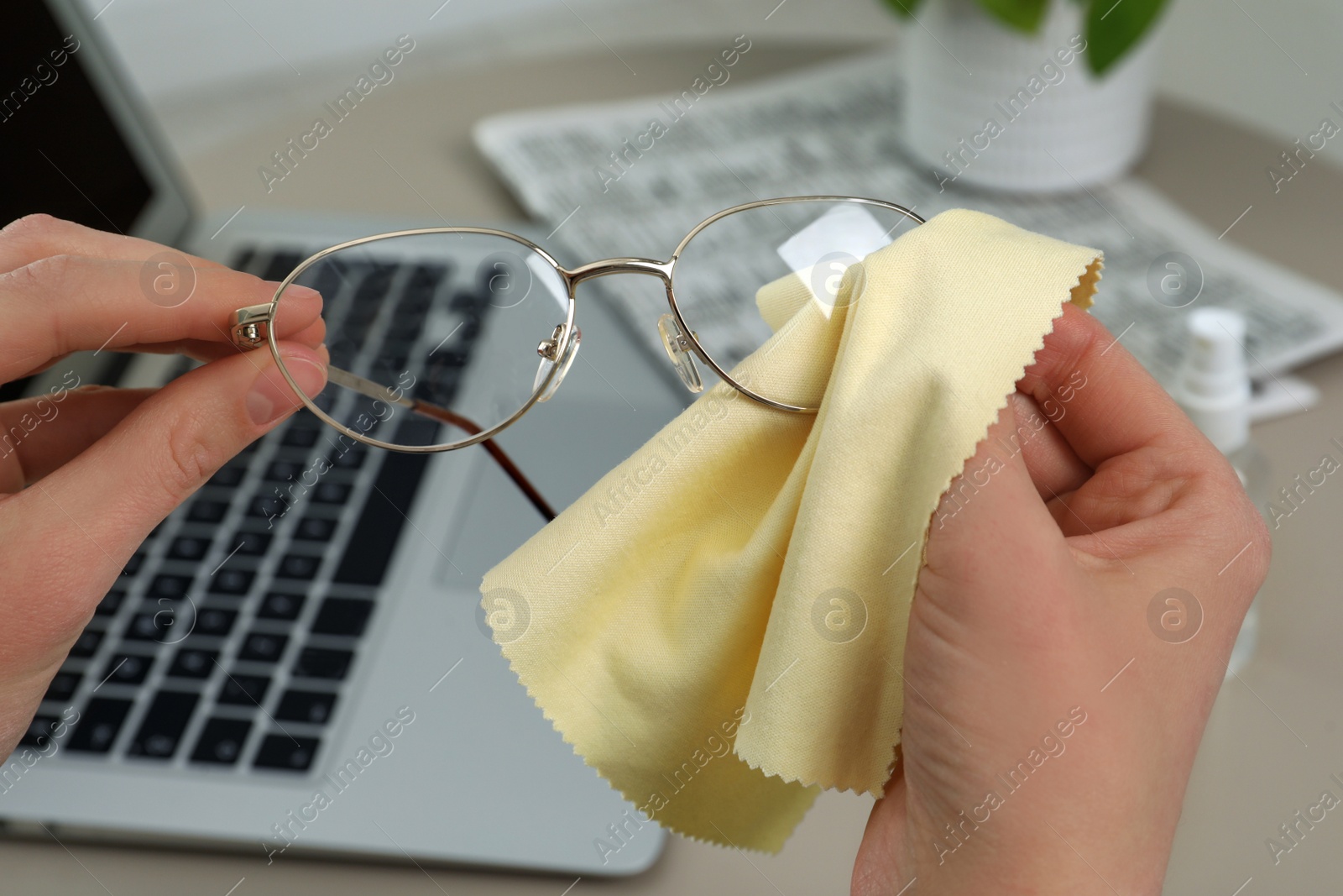 Photo of Woman cleaning glasses with microfiber cloth at home, closeup