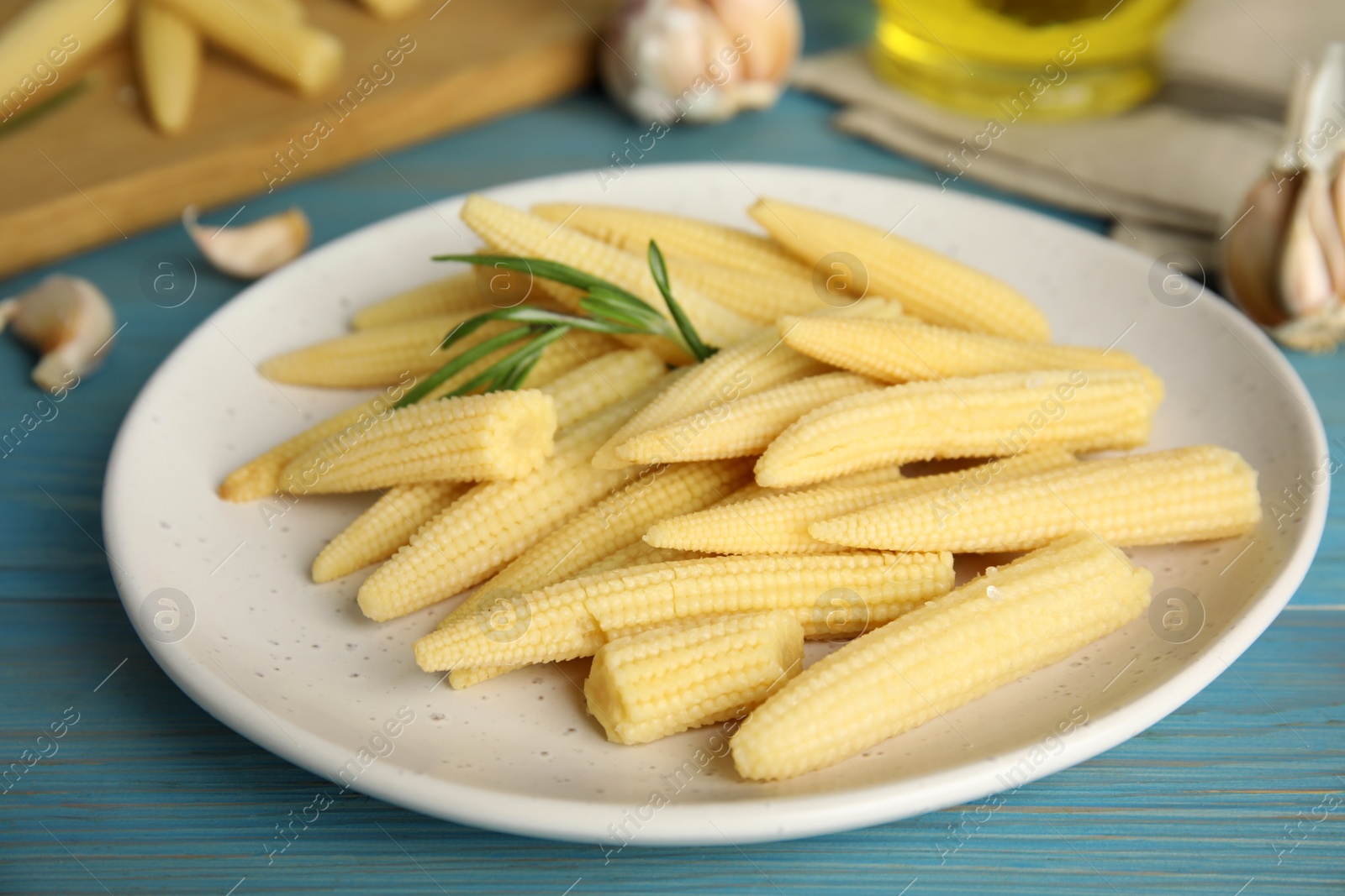 Photo of Fresh baby corn cobs on blue wooden table